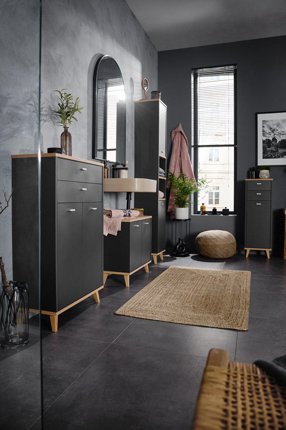Bagno moderno con mobili neri e top effetto legno, specchio ad arco e tappeto in juta.