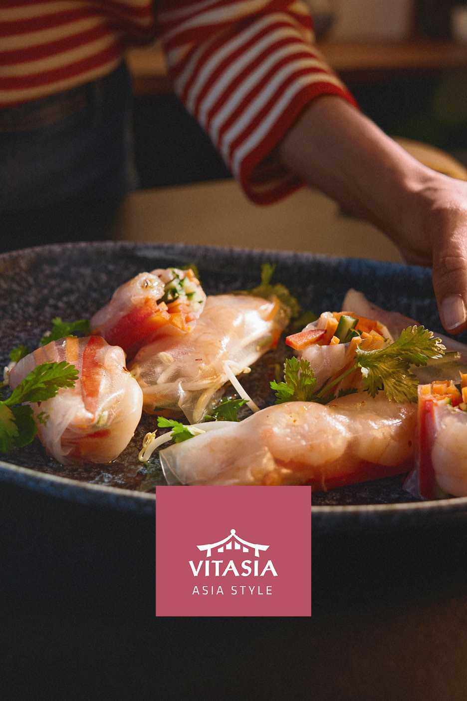 Involtini primavera freschi serviti su un piatto scuro con logo in stile asiatico.