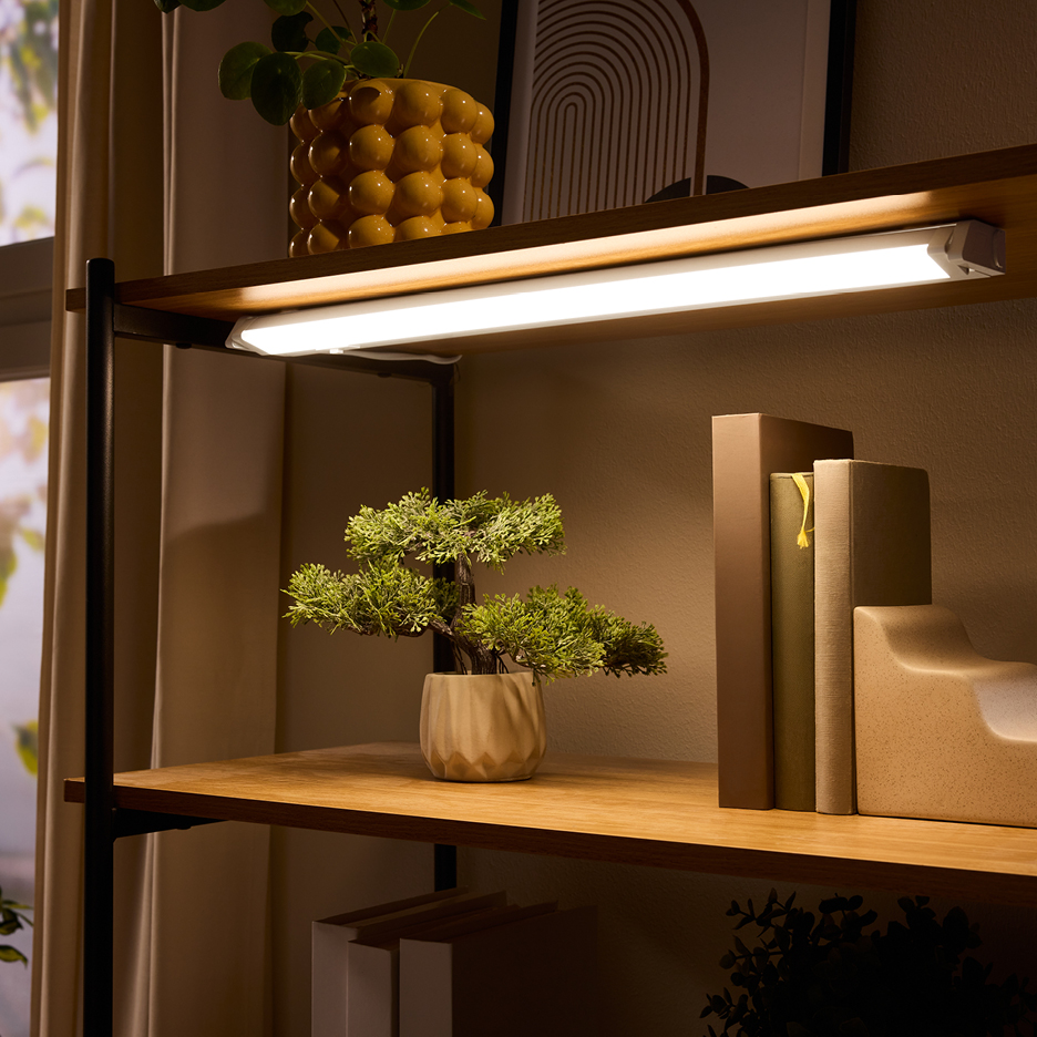 Libreria in legno con illuminazione a LED, piante e libri.