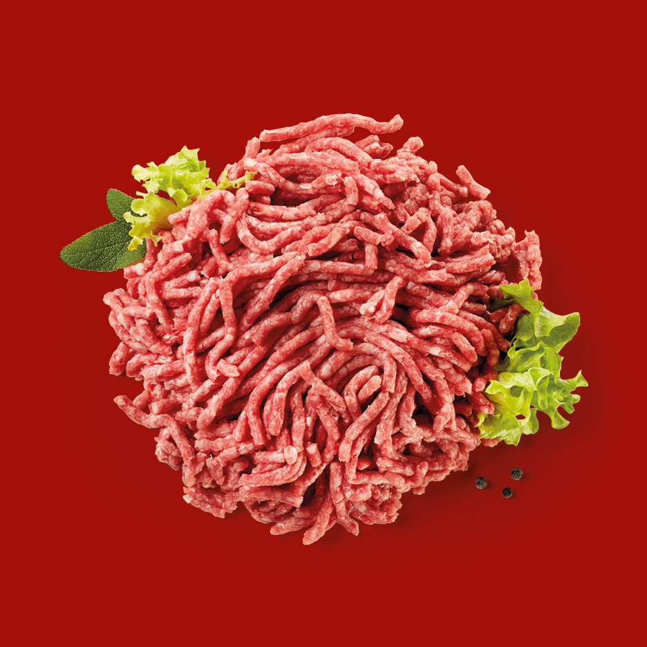 Carne macinata fresca con foglie di lattuga e salvia su sfondo rosso.