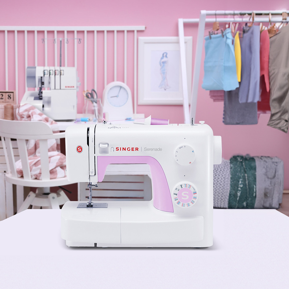 Macchina da cucire Singer bianca e rosa su un tavolo in una stanza rosa.