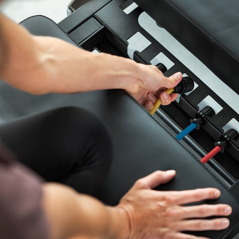 Persona che regola le fasce di resistenza su una panca da esercizio.