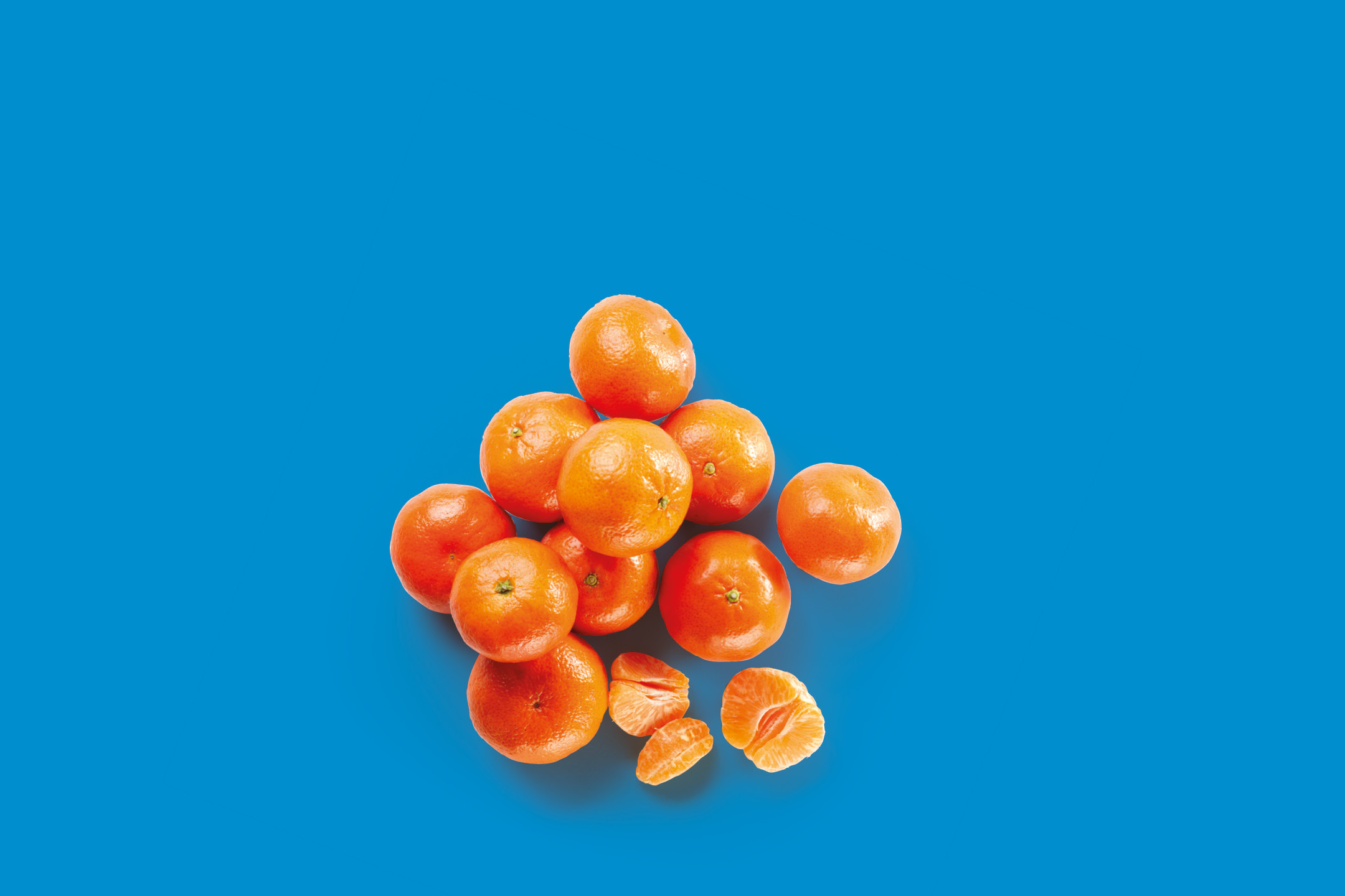 Mandarini freschi e sbucciati su sfondo blu.