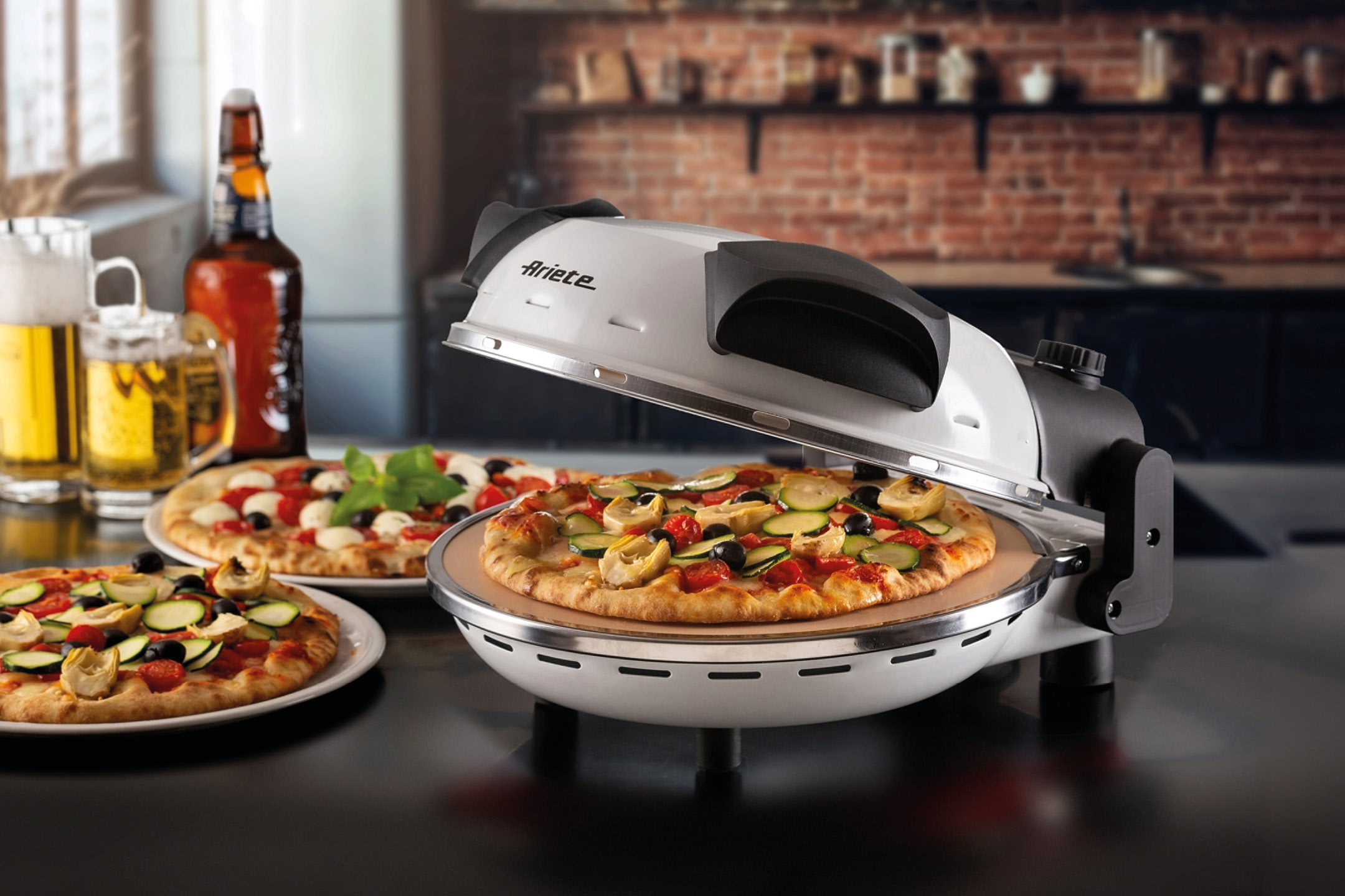 Forno per pizza Ariete con pizza vegetariana e birra in un ambiente da cucina.