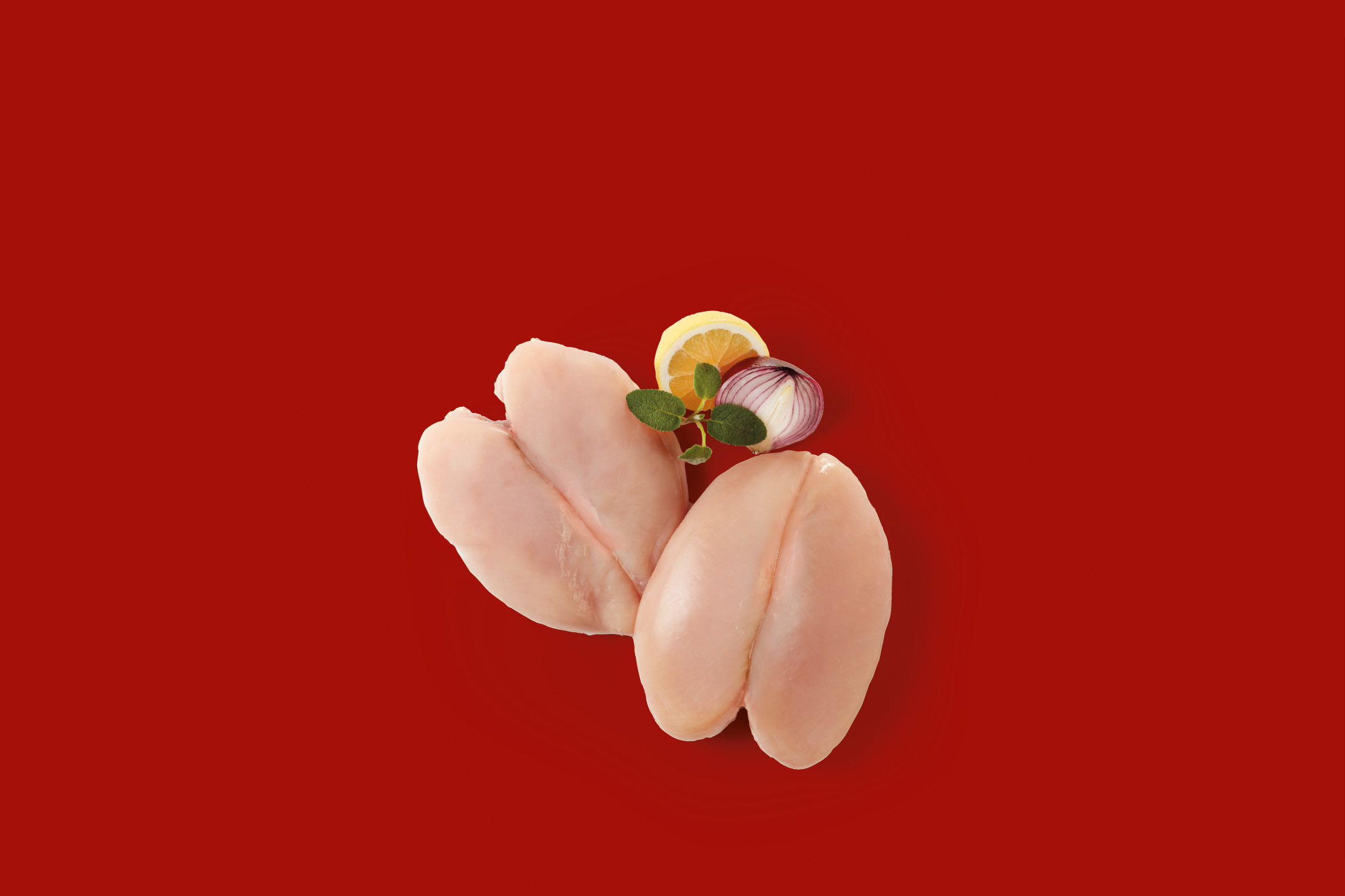 Due petti di pollo crudi con limone, cipolla rossa e origano su sfondo rosso.