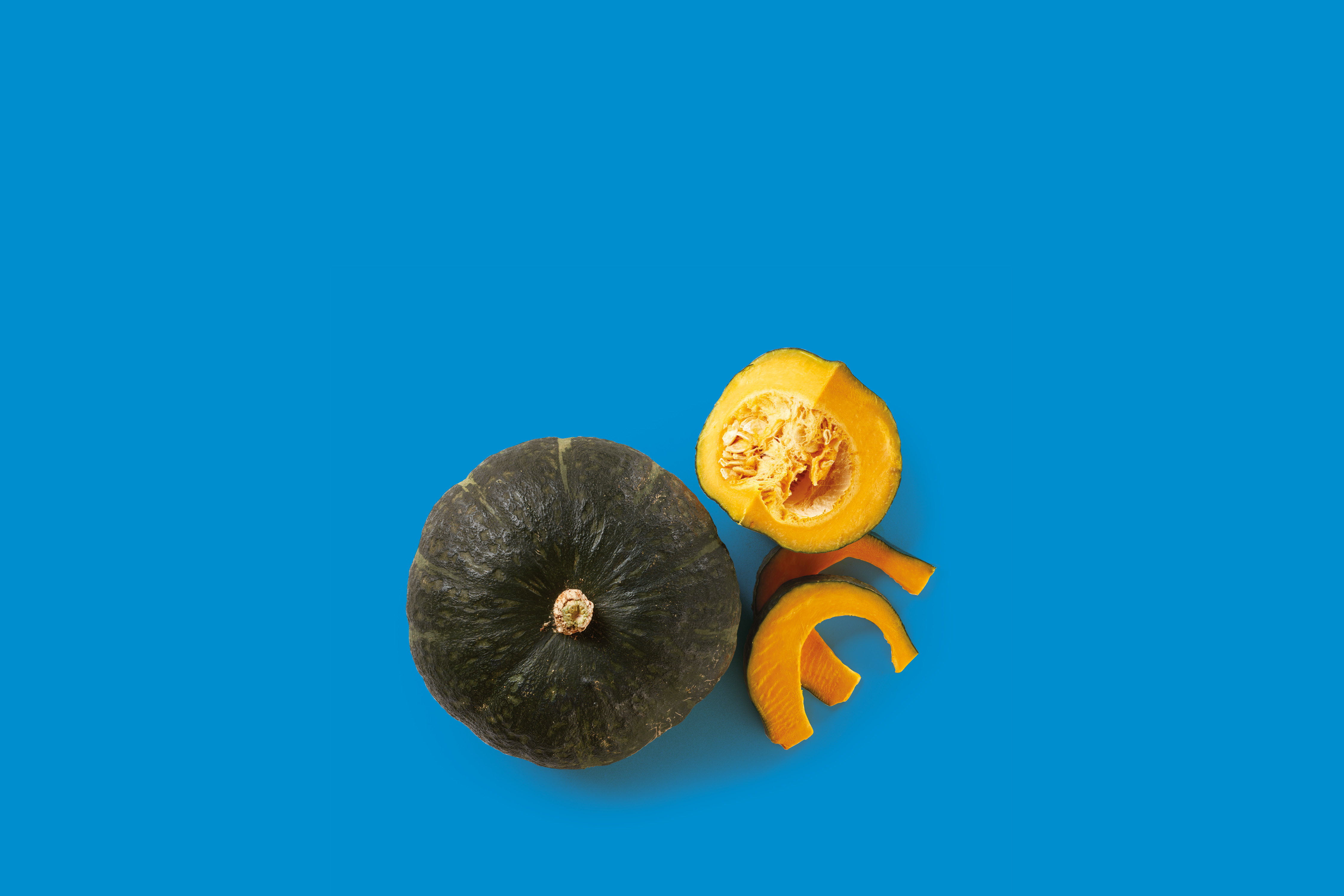 Zucca intera e a fette su sfondo blu.