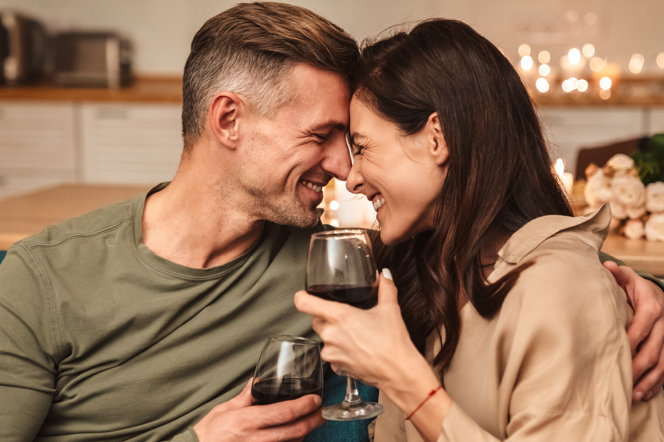Coppia felice che brinda con vino rosso, in un'atmosfera romantica.