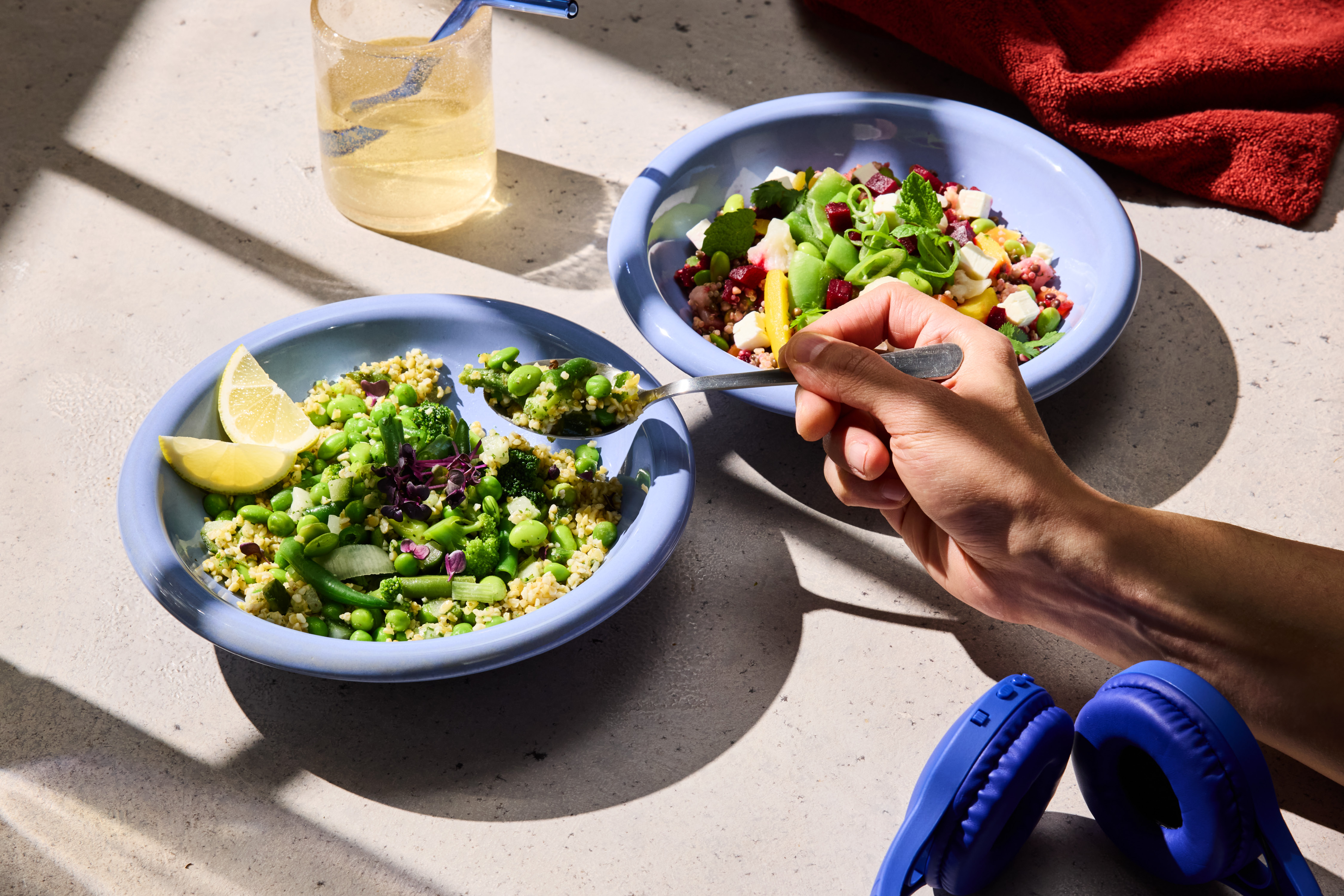Due ciotole di insalata colorata con verdure, formaggio e cereali, una bevanda e cuffie.
