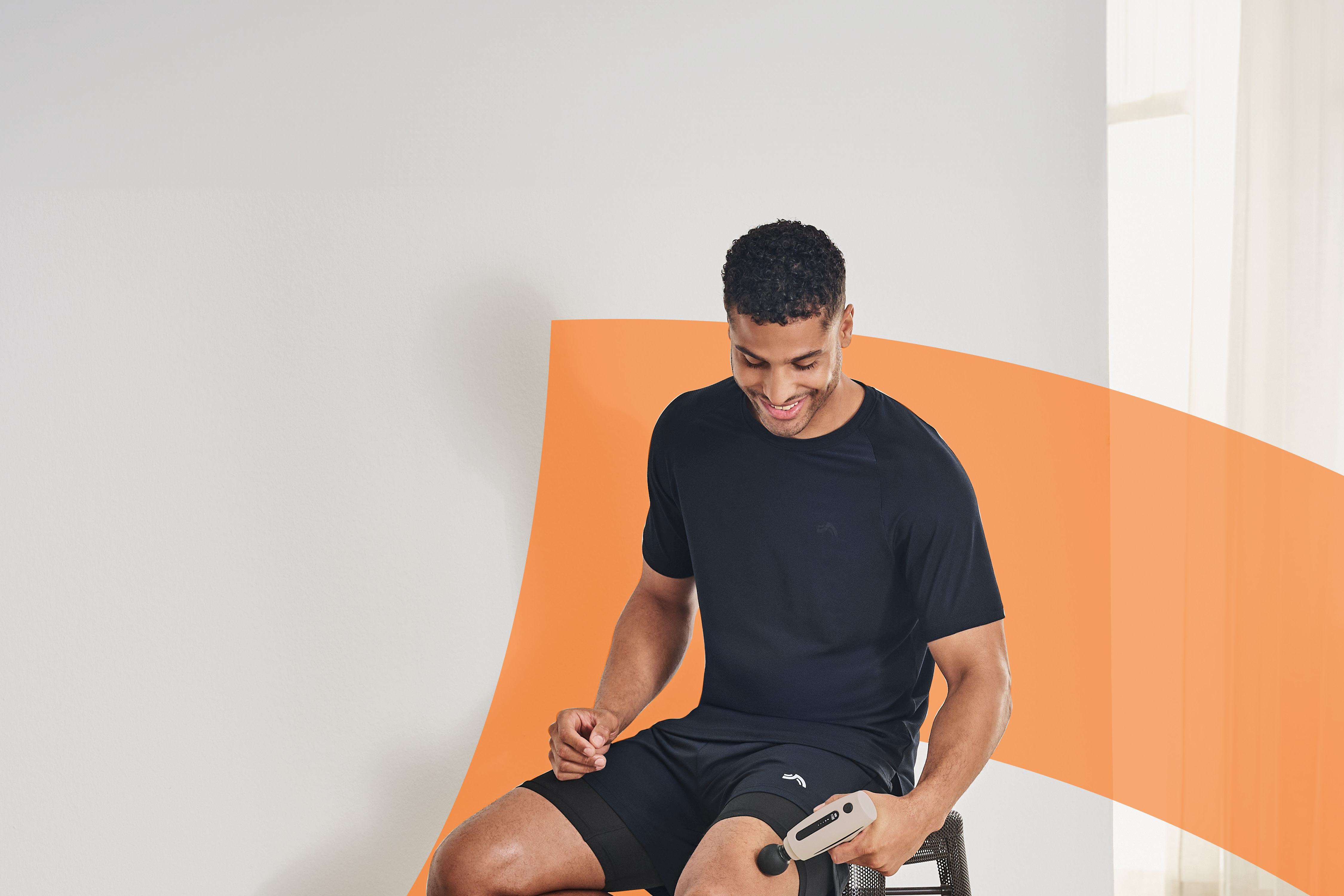 Uomo sorridente che usa un massaggiatore portatile sulla coscia.