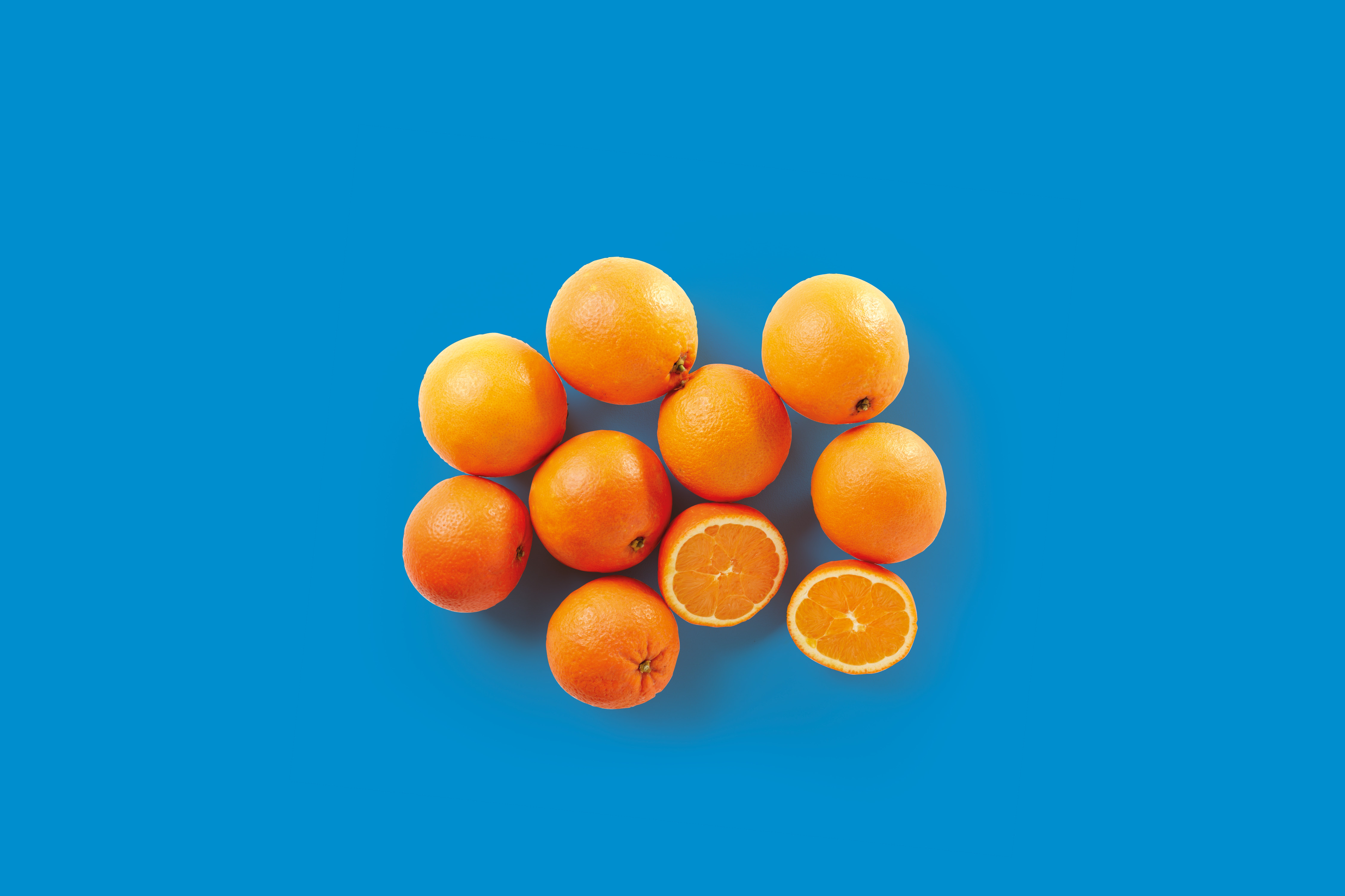 Arance intere e tagliate a metà su sfondo blu.