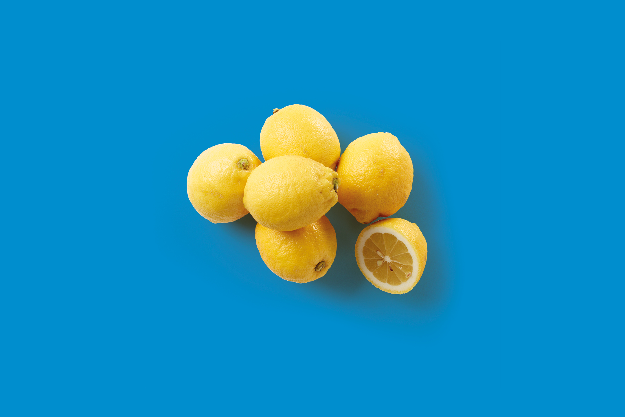 Limoni freschi su sfondo blu, uno tagliato a metà.