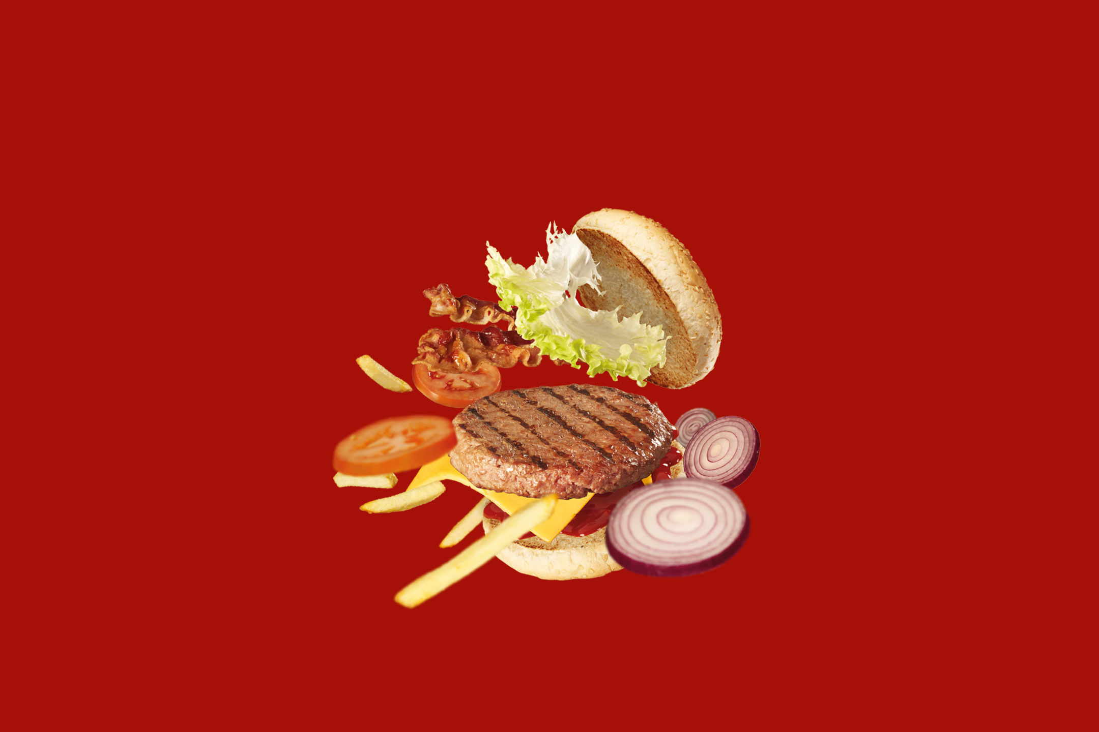 Hamburger con manzo, formaggio, cipolla, pomodoro, patatine fritte, pancetta e lattuga su sfondo rosso.