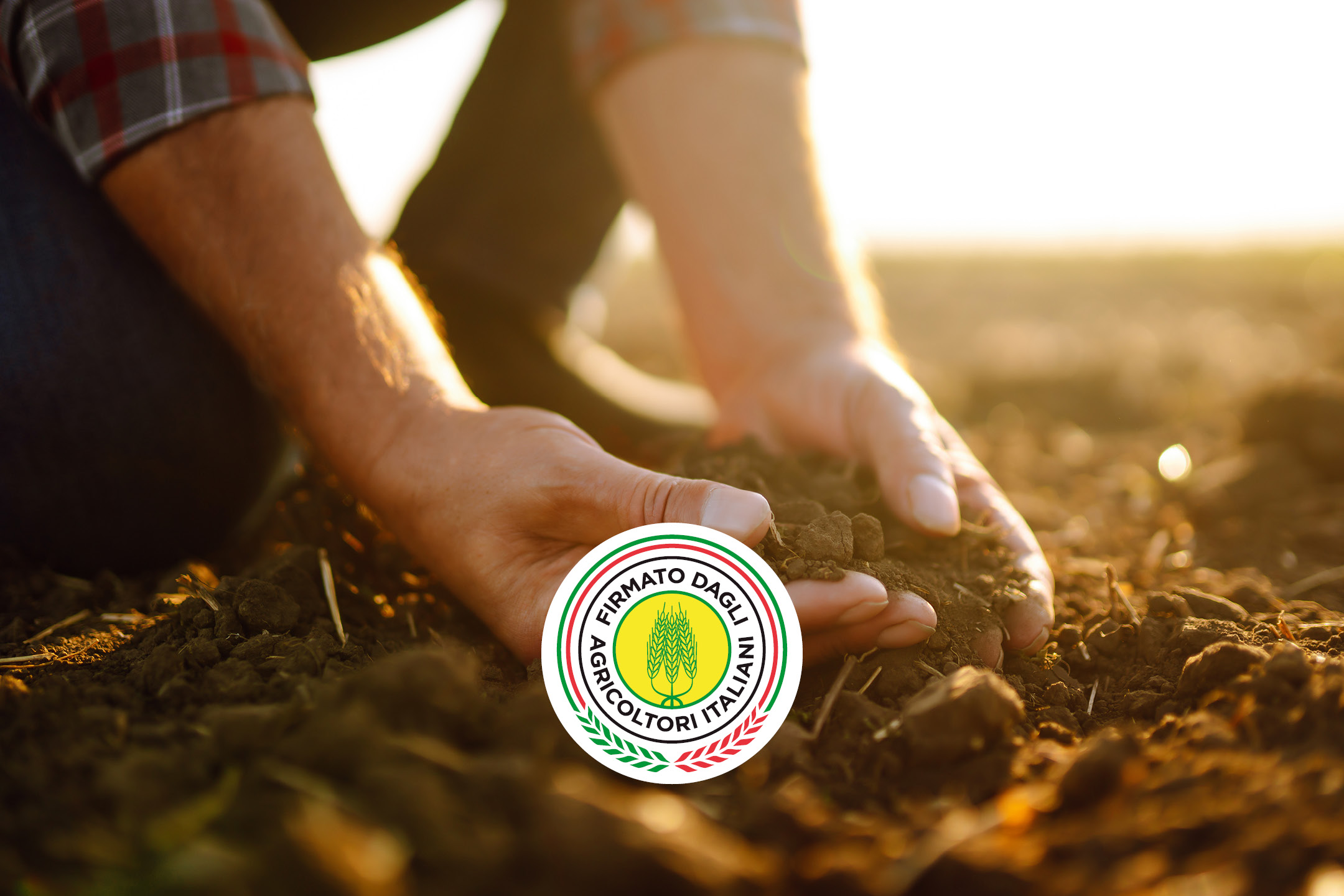 Mani di un agricoltore che tengono del terriccio, con un logo circolare al centro.