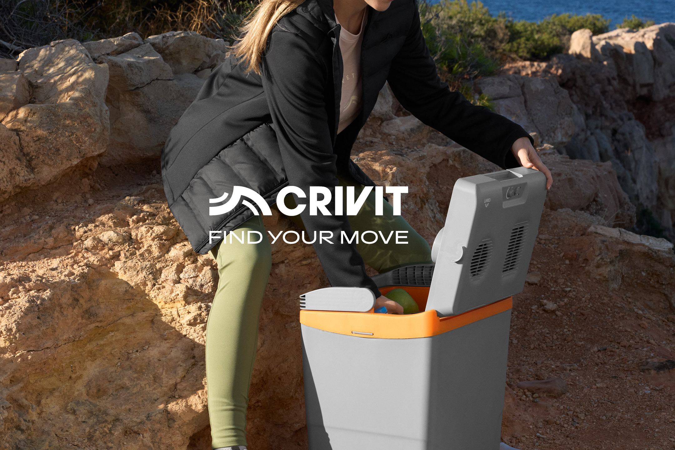 Donna in abbigliamento sportivo apre un frigo portatile in un paesaggio roccioso. Testo: 'FIND YOUR MOVE'.