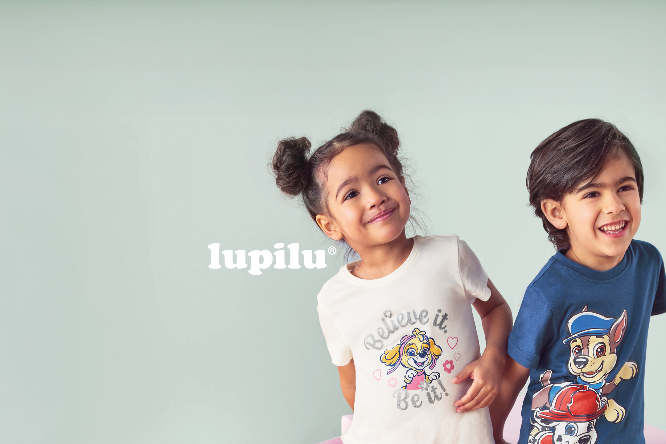 Due bambini sorridenti indossano magliette con stampe di personaggi dei cartoni animati.