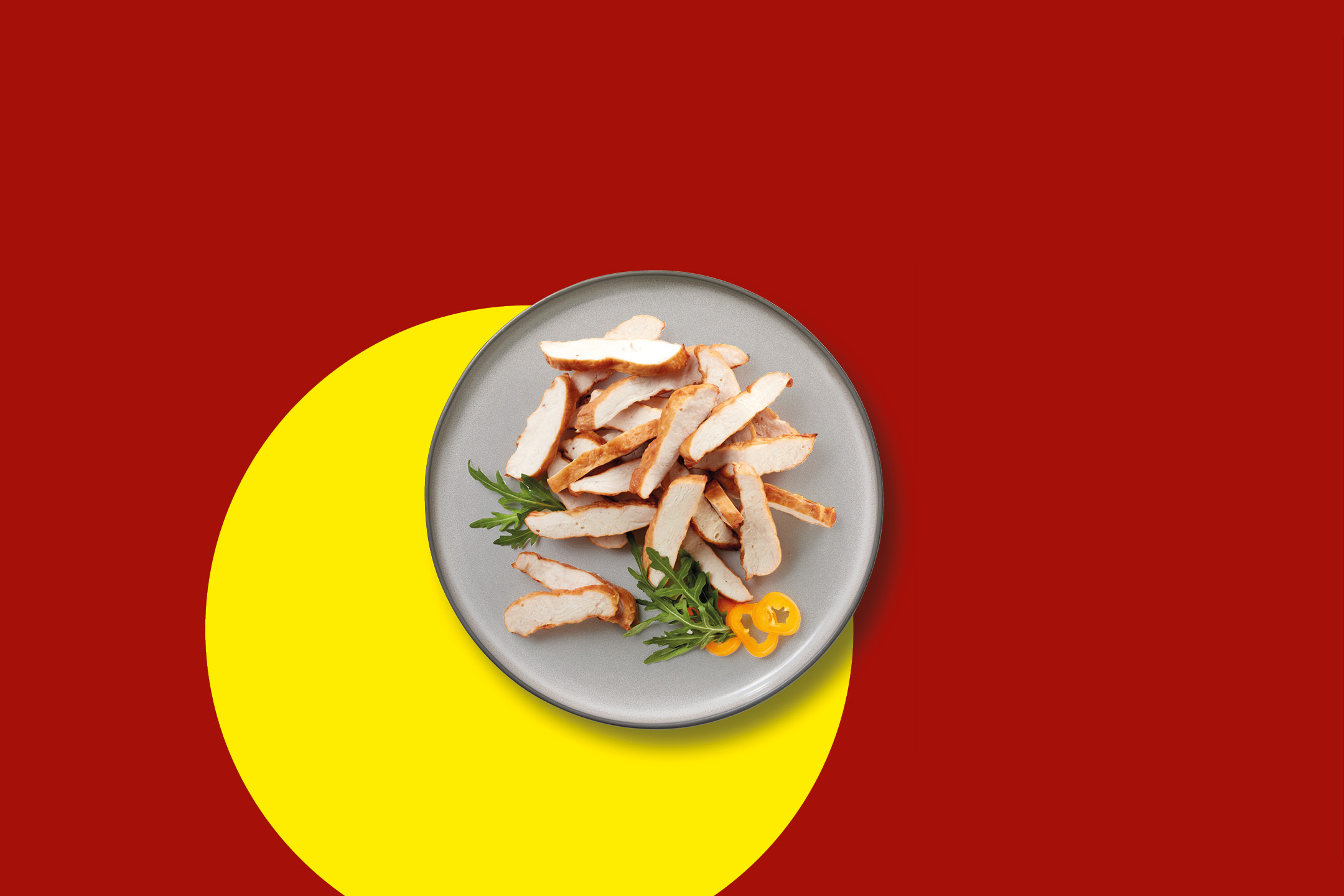 Fettine di pollo grigliate con rucola e peperoni gialli su un piatto grigio.
