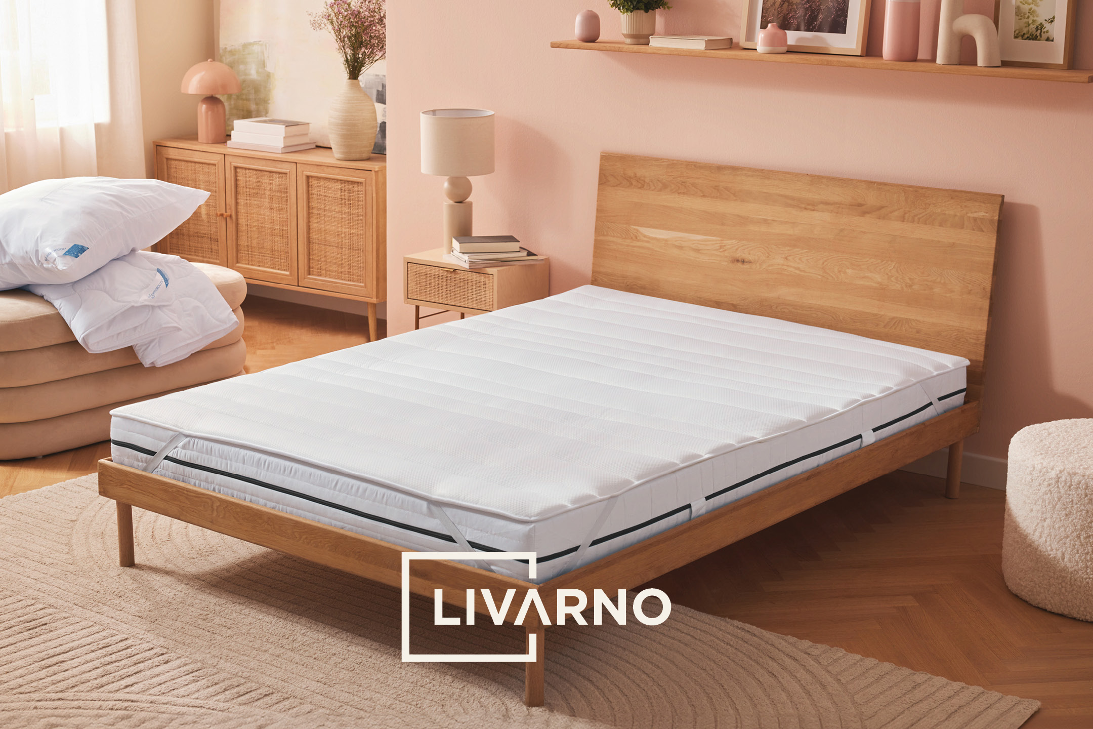 Camera da letto con materasso, letto in legno, comodino e cuscini bianchi, stile moderno.