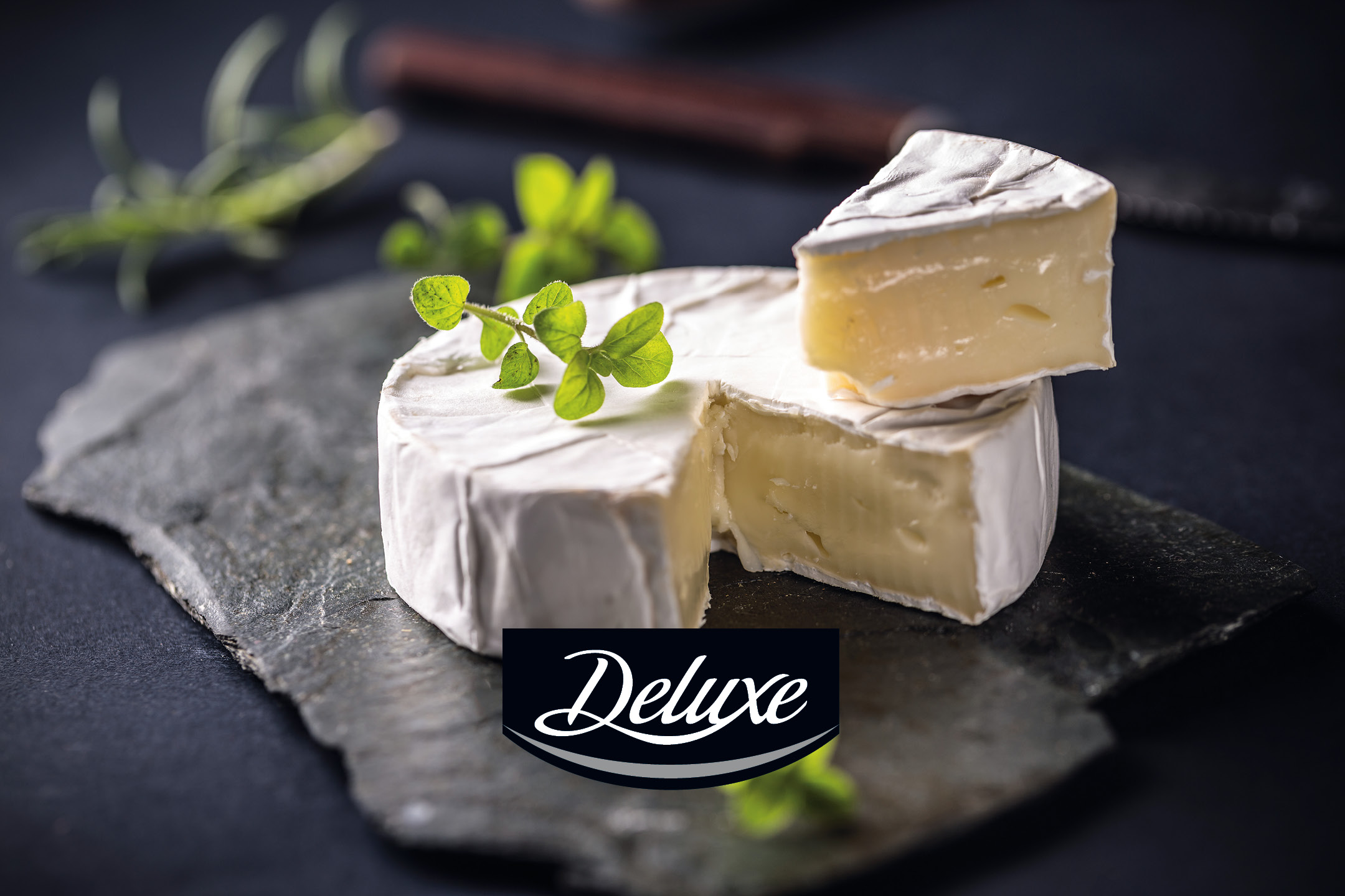 Formaggio camembert con erbe aromatiche su un tagliere di ardesia.