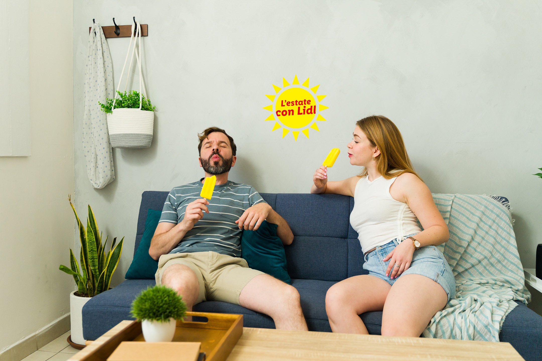 Coppia sul divano che mangia ghiaccioli, con la scritta 'L'estate con Lidl' e piante d'appartamento.