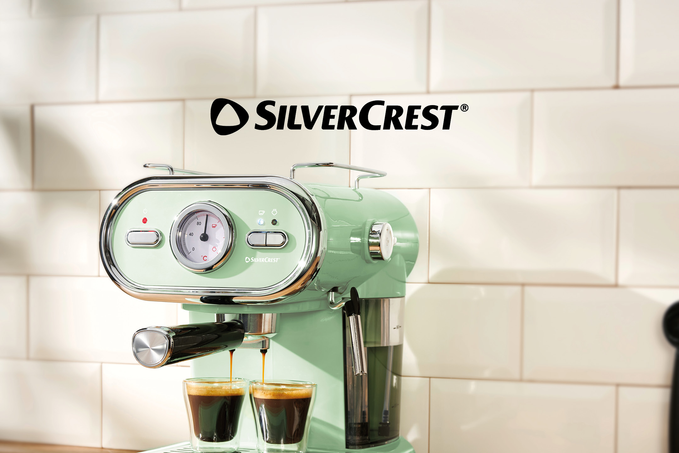 Macchina da caffè espresso retrò verde menta che eroga caffè in due tazzine di vetro.