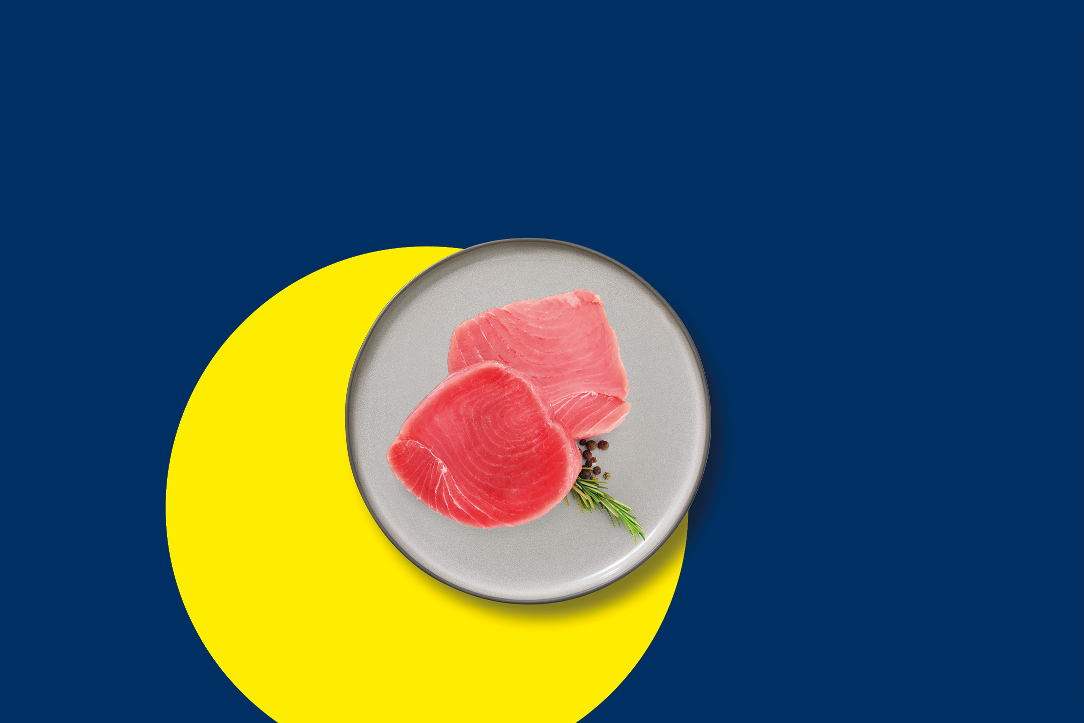 Tranci di tonno fresco su un piatto grigio con rosmarino e pepe nero.