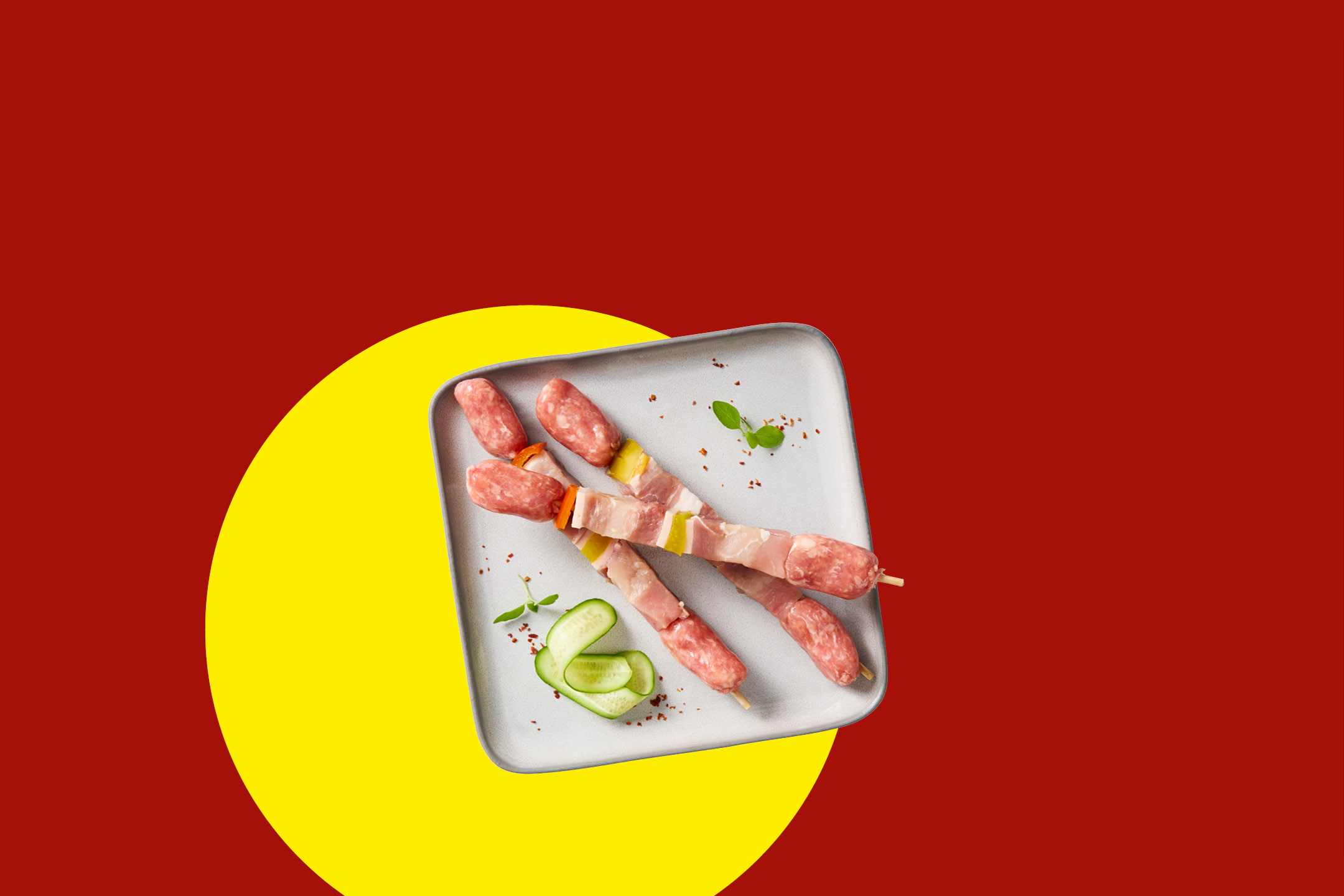 Spiedini di carne cruda con pancetta e verdure su un piatto grigio.