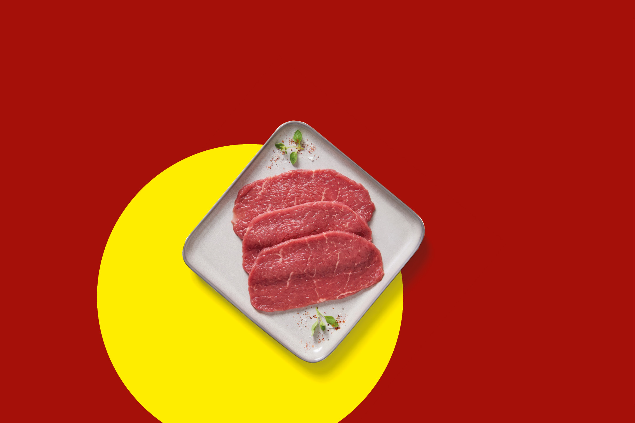 Tre fette di carne bovina fresca su un piatto, sfondo rosso e giallo.