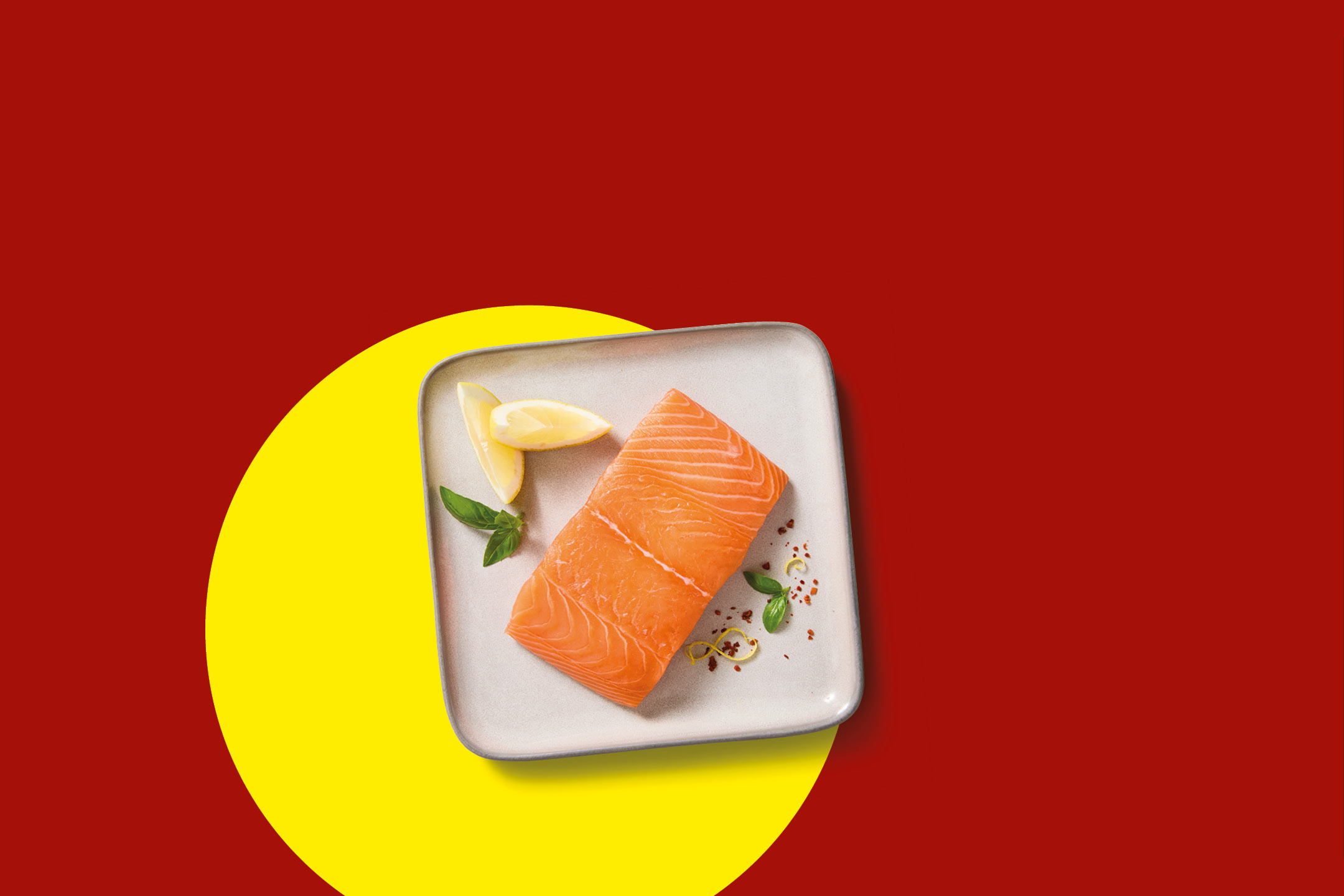Filetto di salmone fresco servito su un piatto con spicchi di limone ed erbe aromatiche.