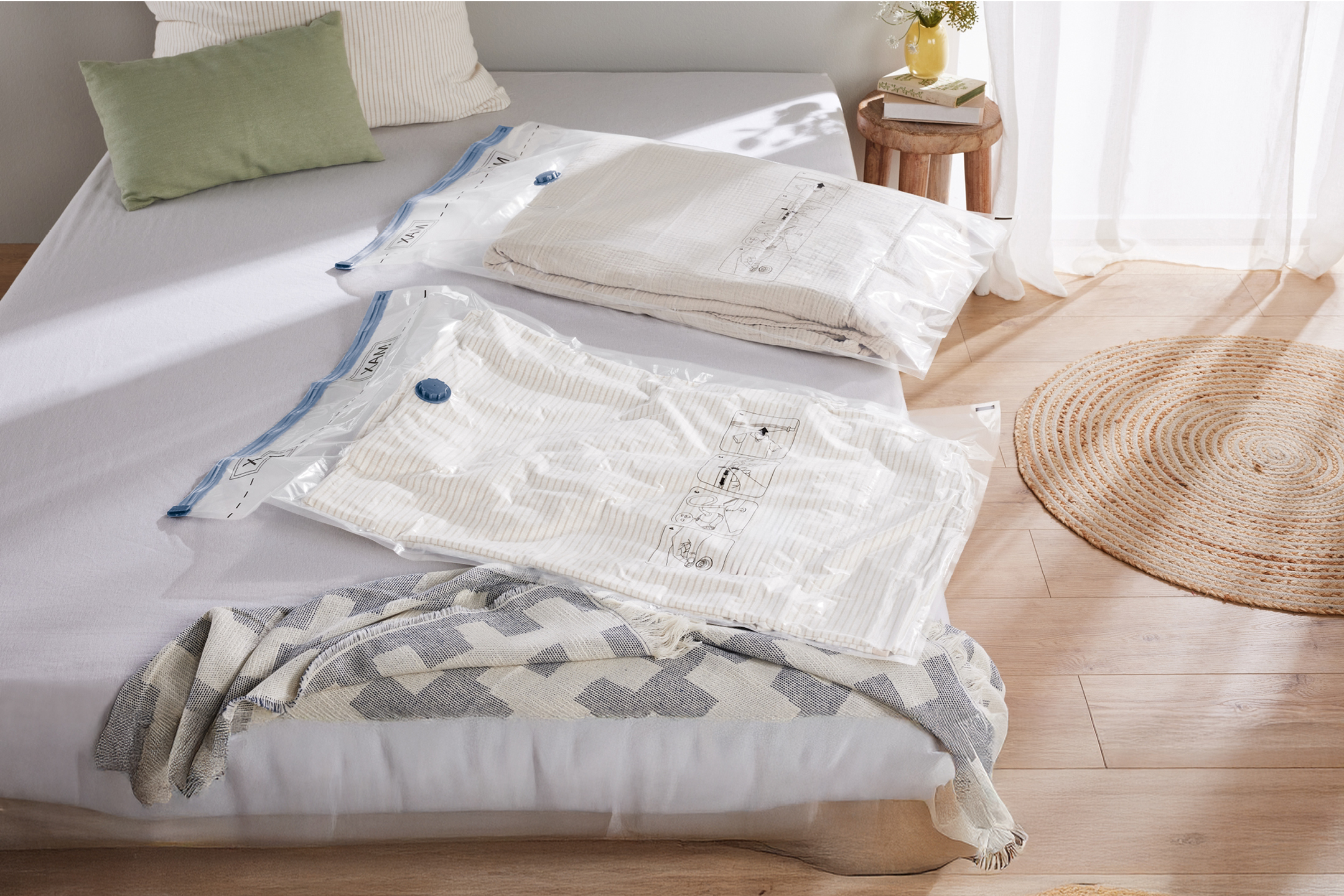 Due sacchi sottovuoto con coperte su un letto, con cuscini e un tappeto.