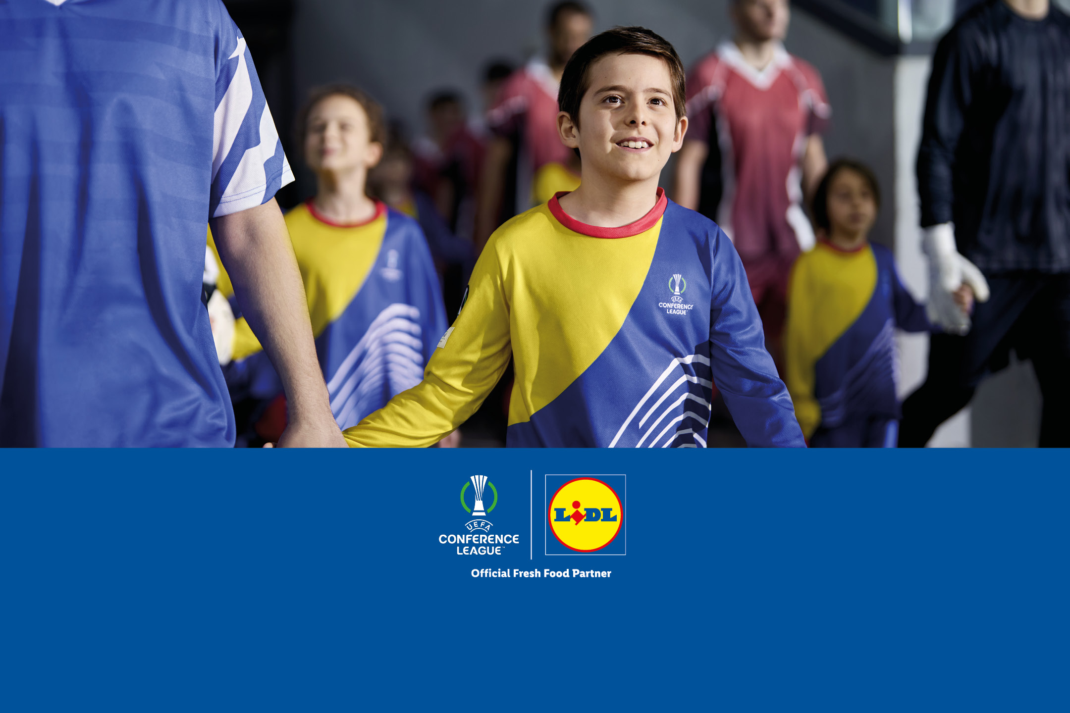 Bambini che entrano in campo con la divisa ufficiale della UEFA Conference League.