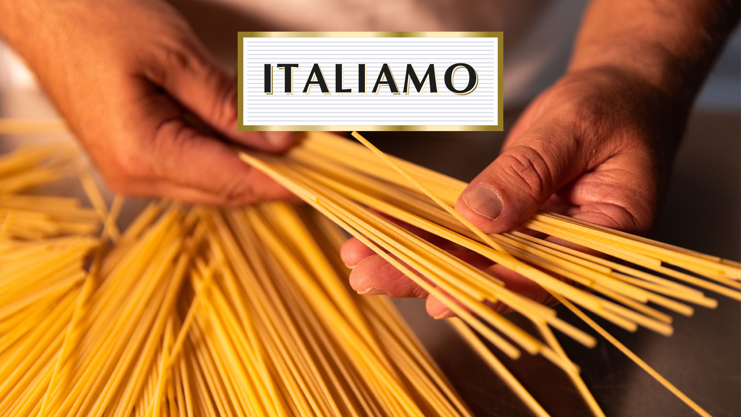 Mani che tengono spaghetti crudi con la scritta 'ITALIAMO'.