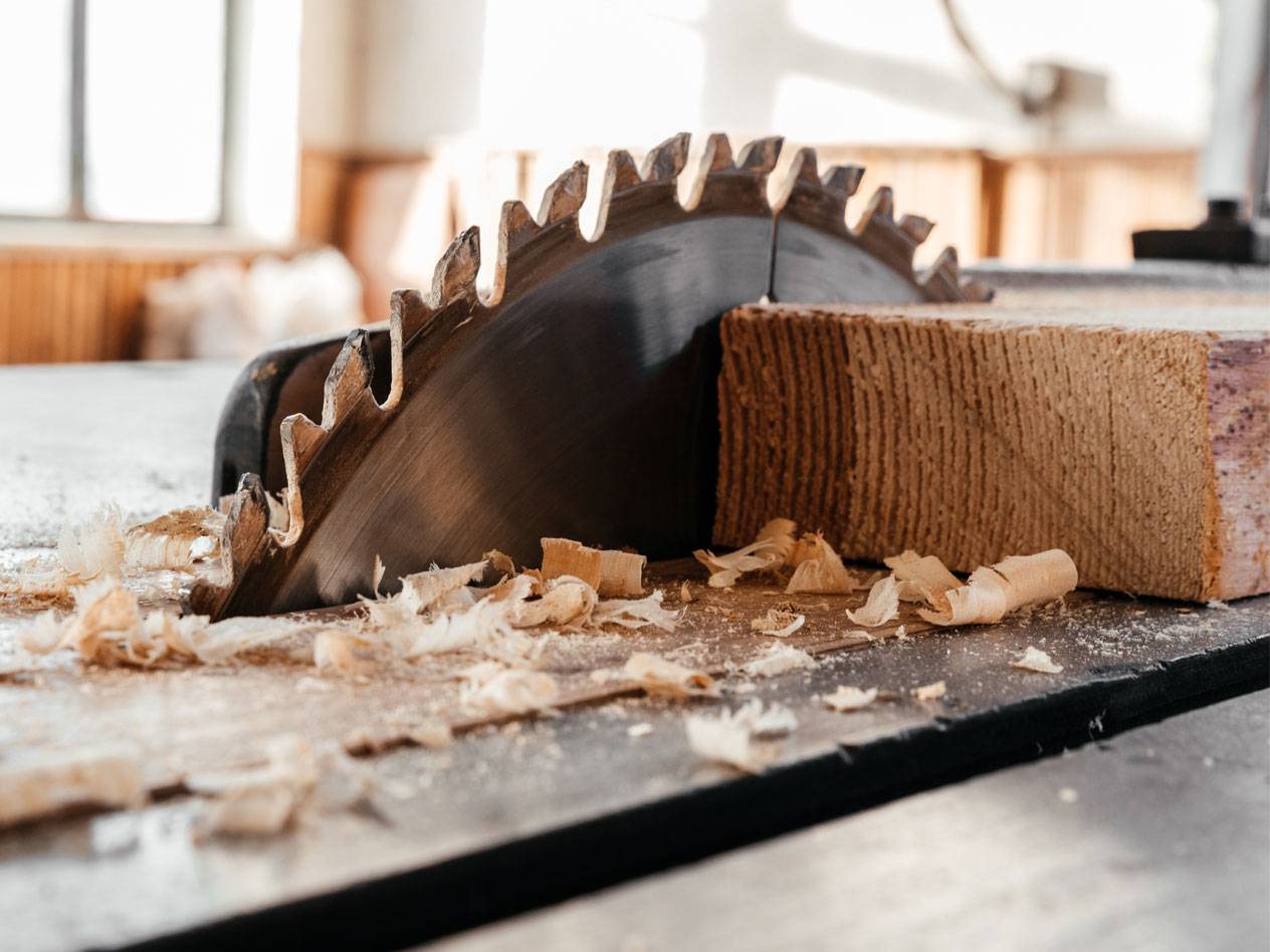 Pezzi di legno e una sega circolare in un laboratorio.