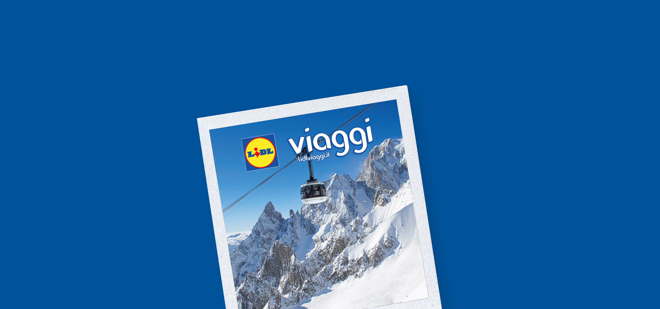 Paesaggio montano innevato con cime rocciose e cielo azzurro, con funivie in primo piano.