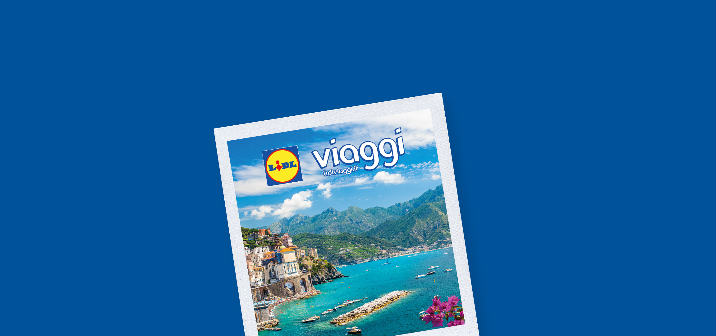 Paesaggio costiero italiano con case colorate, montagne verdi e mare blu con barche.