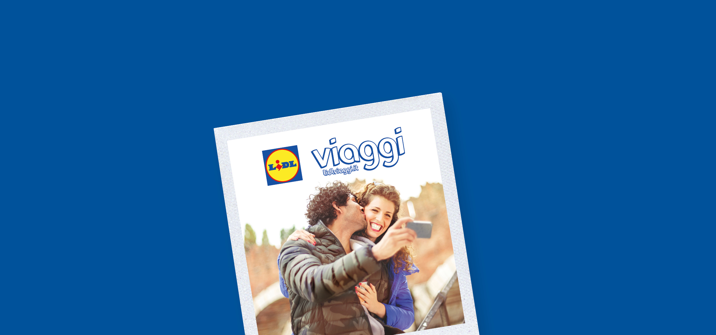 Una coppia felice si scatta un selfie, con un uomo che bacia la donna sulla guancia, sullo sfondo di un castello.