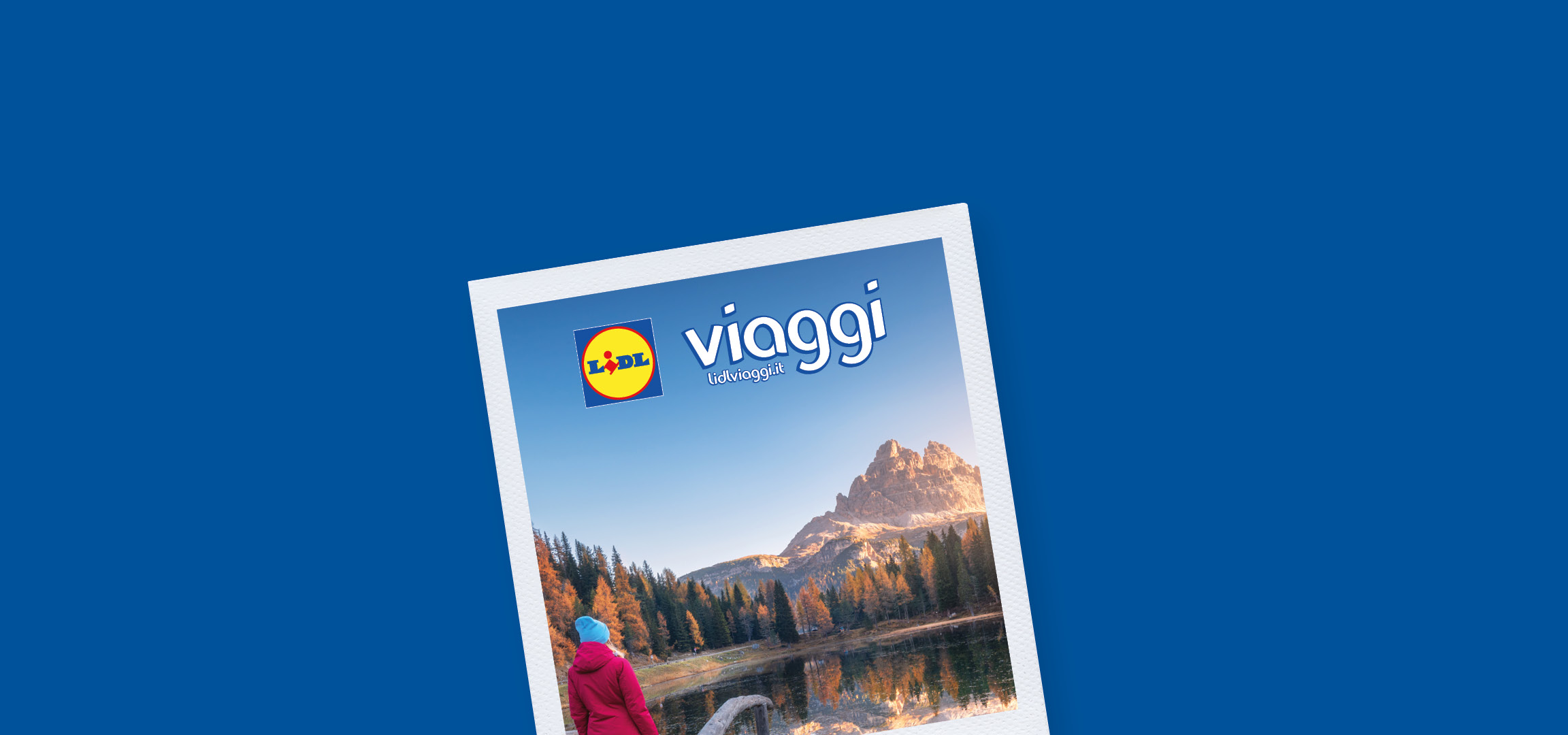 Donna in giacca rossa e cappello blu che guarda un lago di montagna con alberi autunnali e il logo Lidl Viaggi.