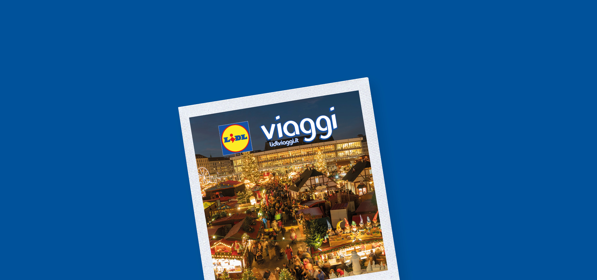 Mercatino di Natale affollato con bancarelle illuminate, giostre e l'insegna Lidl Viaggi.