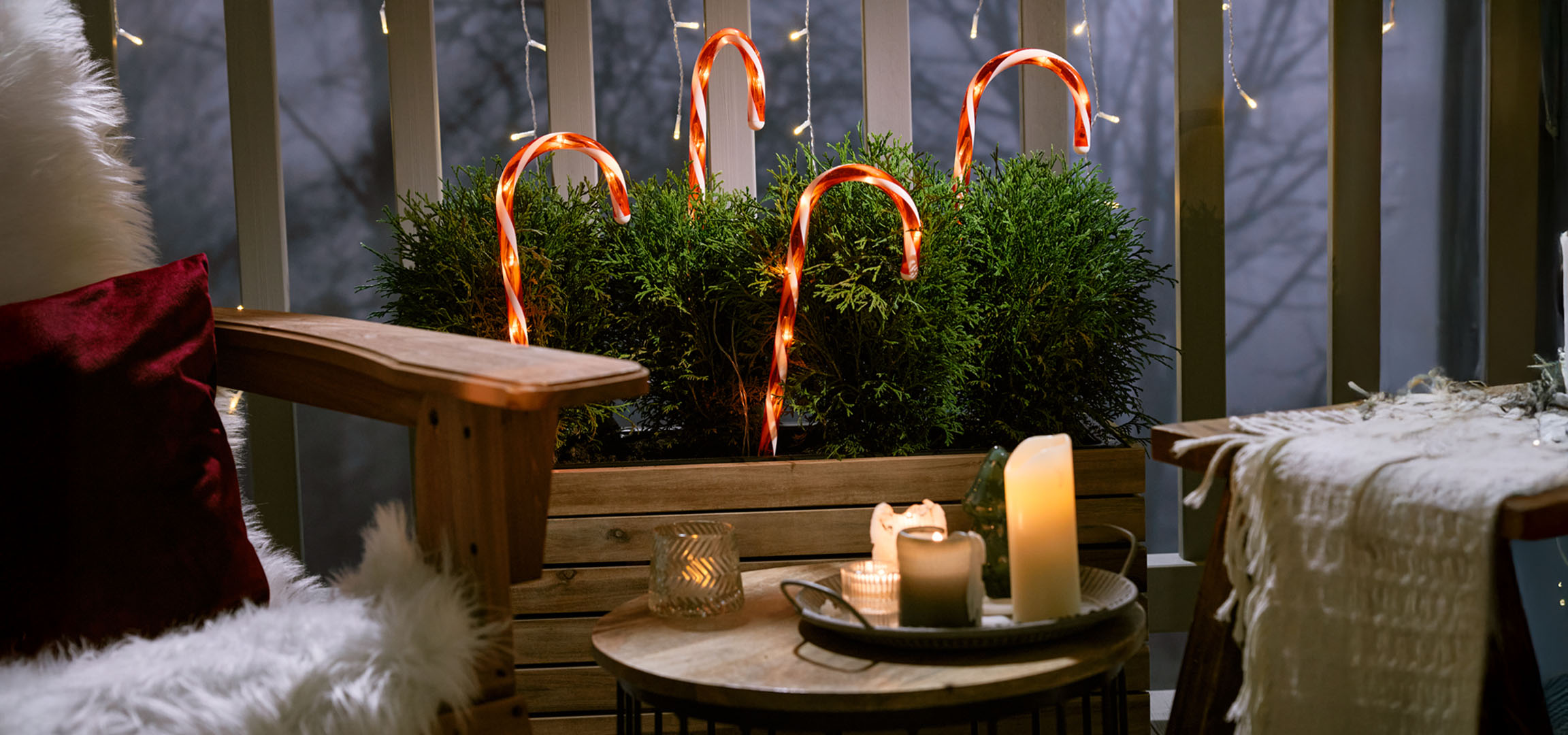 Balcone decorato a Natale con una sedia, candele e bastoncini di zucchero.