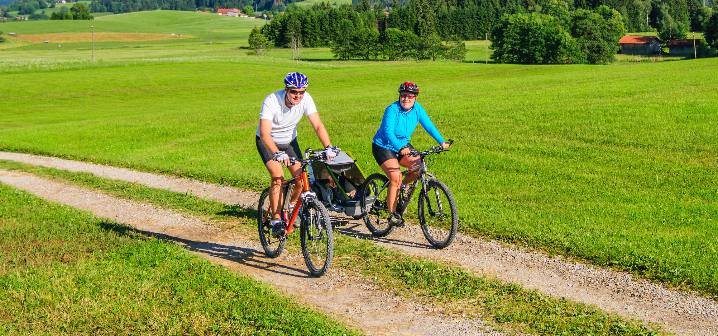 Coppia in bicicletta in un paesaggio verde.