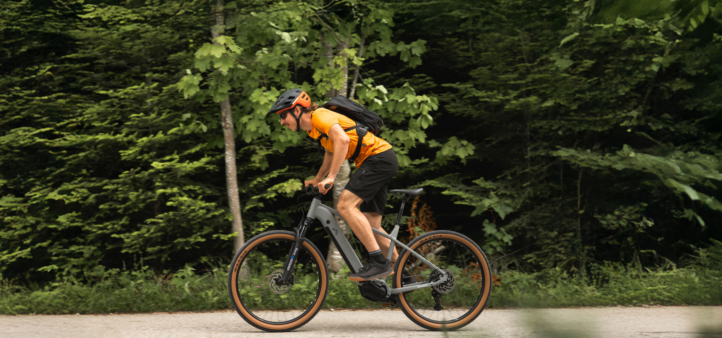 Un uomo in sella a una e-bike Cube su un sentiero nel bosco.