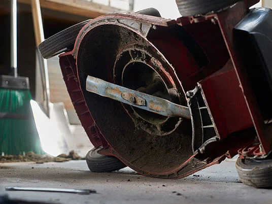 Tosaerba sporco capovolto, con lama visibile