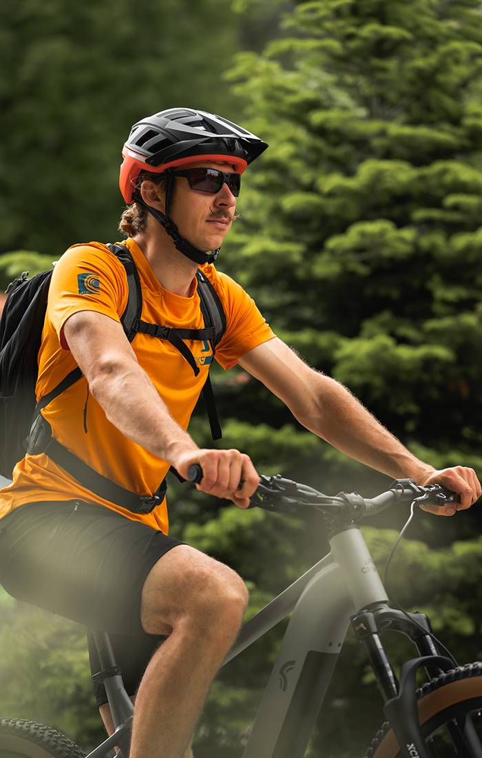 Uomo in bici da montagna con casco e abbigliamento sportivo.