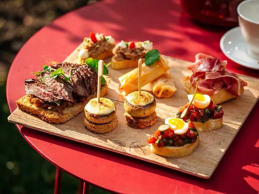 Assortimento di tapas e tartine, inclusi bistecca, funghi, involtini primavera e bruschetta.