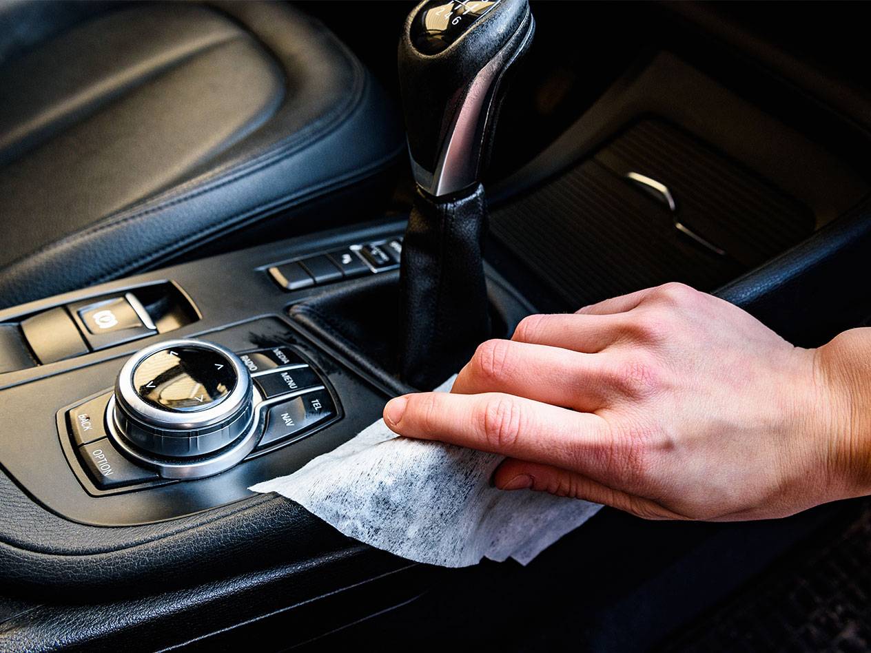 Mano che pulisce l'interno di un'auto con una salvietta umida.