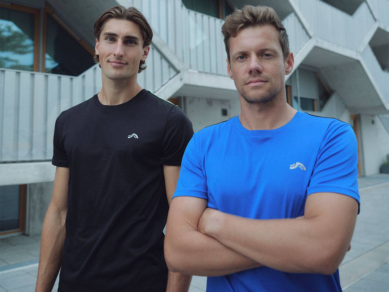 Due uomini in magliette sportive nere e blu con logo.