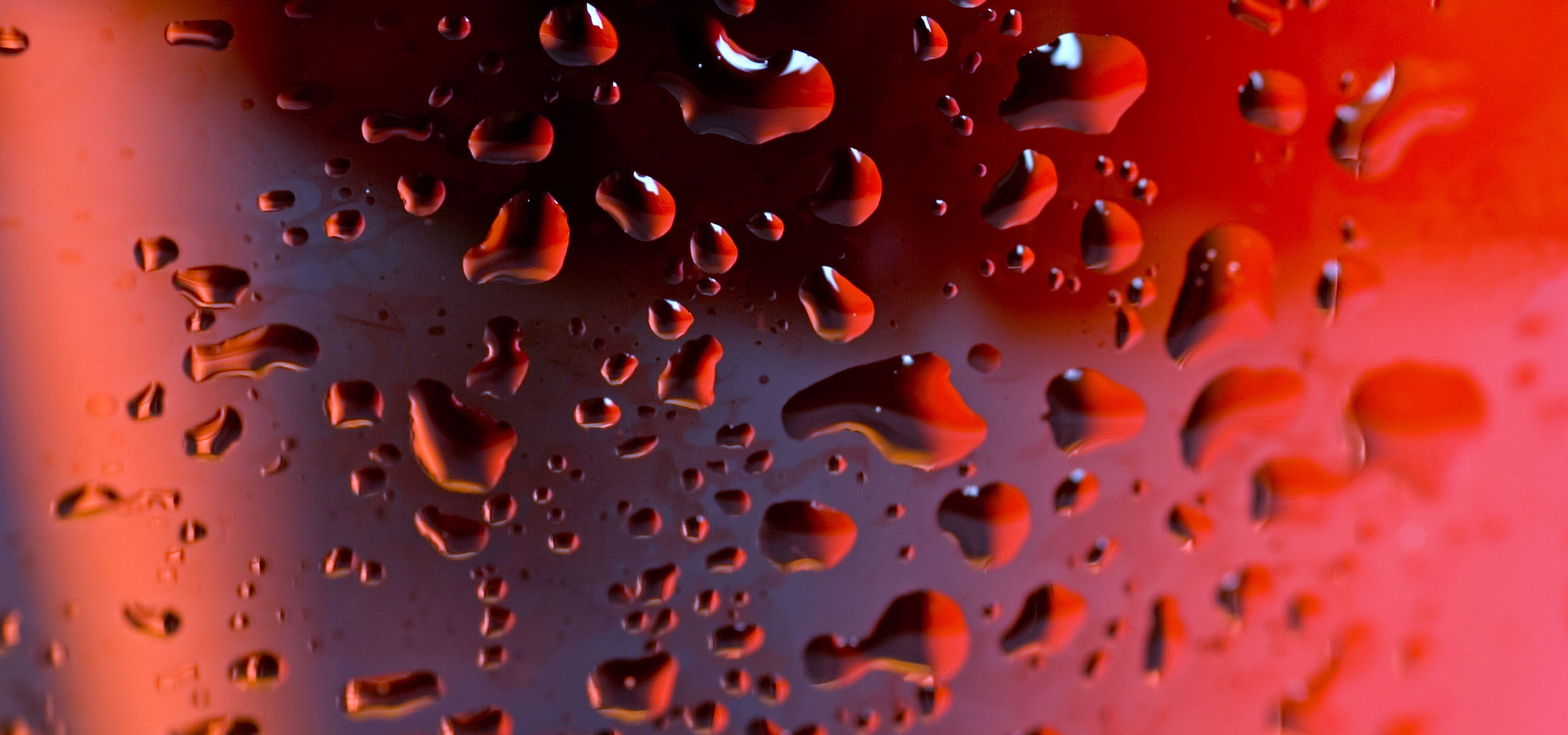 Gocce d'acqua rosse su una superficie con uno sfondo sfocato