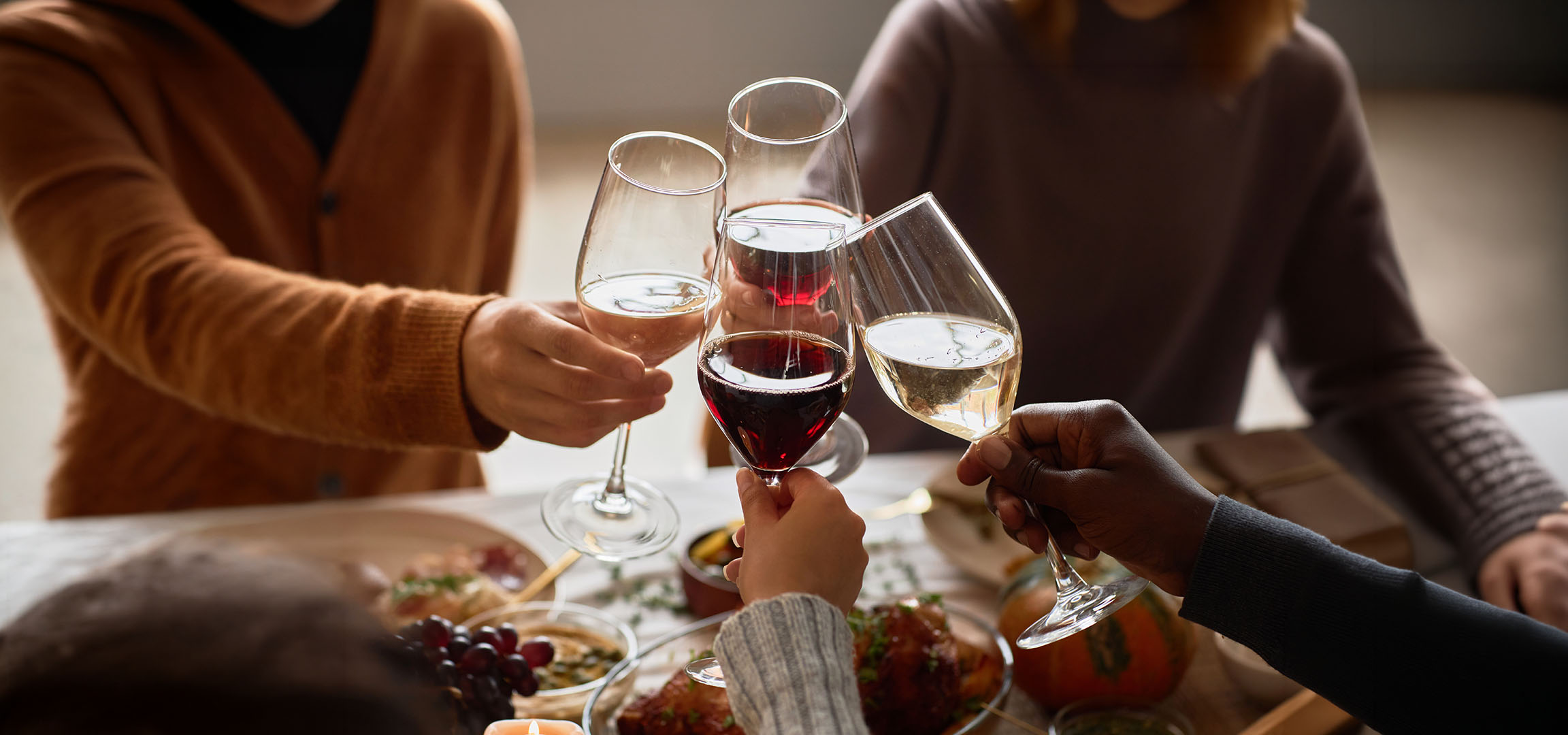 Persone che brindano con bicchieri di vino rosso e bianco.