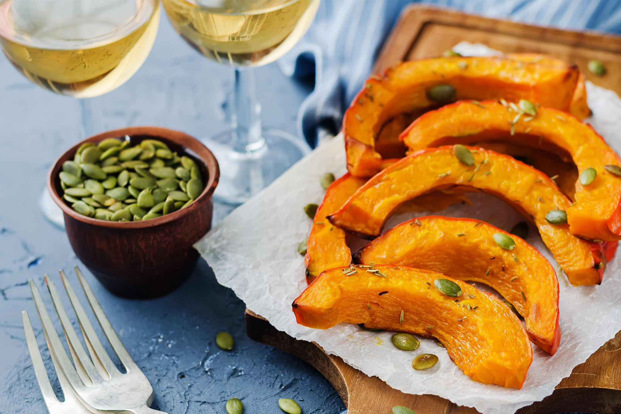 Spicchi di zucca arrostiti con semi di zucca e rosmarino, serviti con vino bianco.