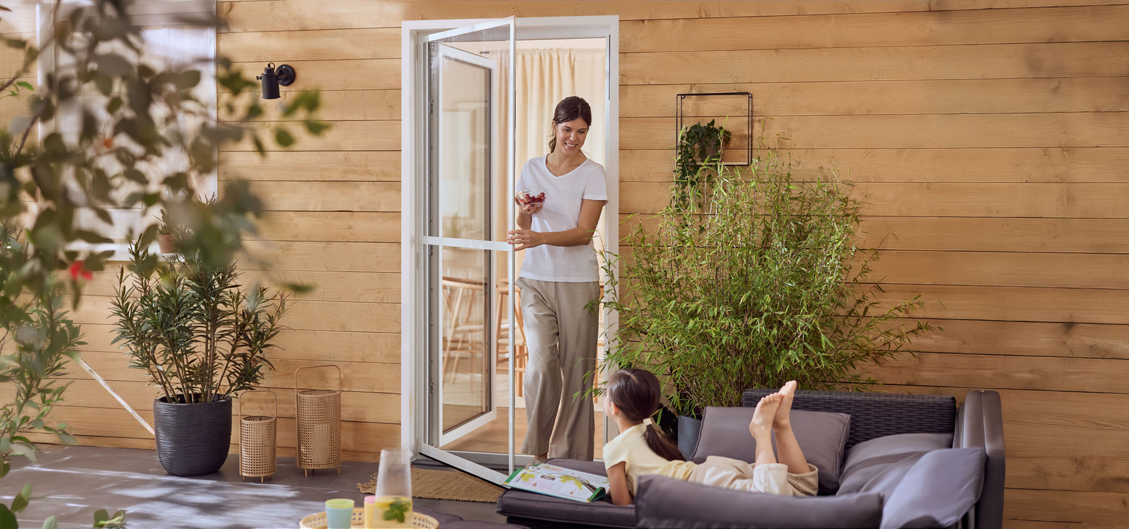 Donna e bambina che si godono un patio con mobili da esterno e piante.