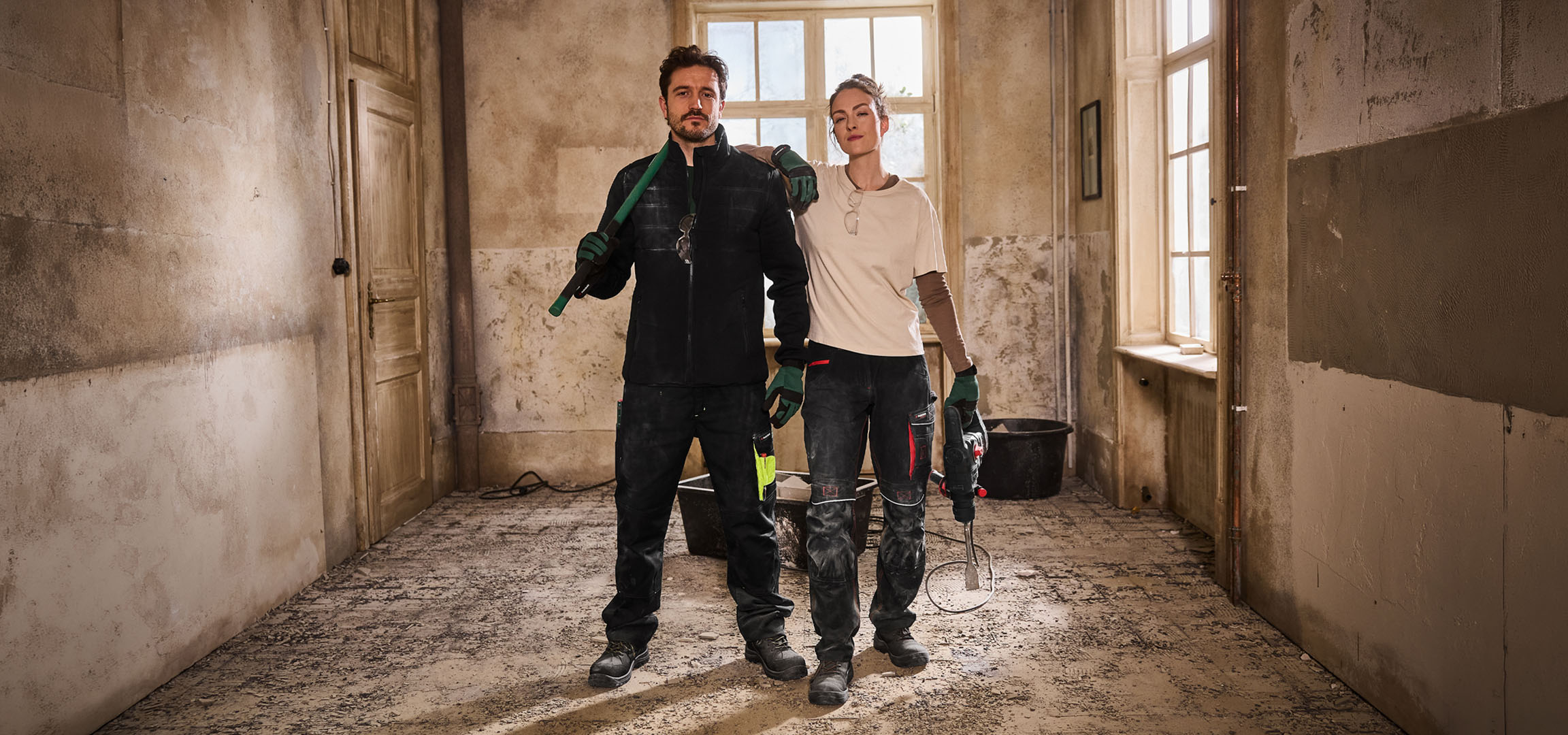 Due operai edili in abiti da lavoro con attrezzi in un cantiere.